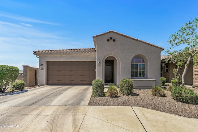 mediterranean / spanish home with a garage, a tile roof, and stucco siding
