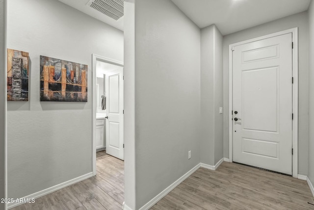 foyer entrance featuring baseboards, visible vents, and light wood-type flooring
