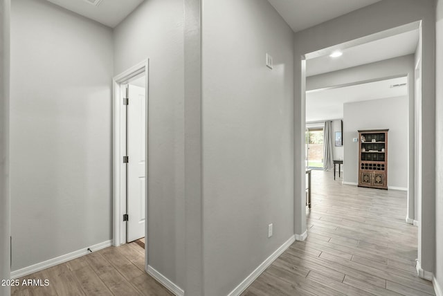 corridor featuring baseboards and wood finished floors