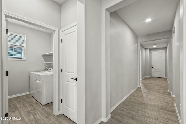 corridor with light wood-type flooring, baseboards, and washer and dryer