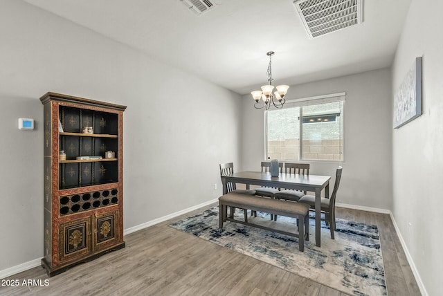 dining space featuring an inviting chandelier, wood finished floors, visible vents, and baseboards