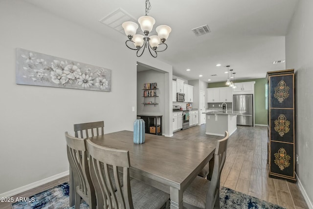 dining room with baseboards, visible vents, an inviting chandelier, recessed lighting, and wood finished floors