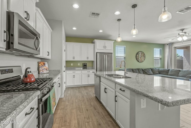 kitchen featuring open floor plan, appliances with stainless steel finishes, a sink, and visible vents
