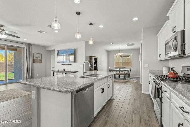 kitchen with a sink, a center island with sink, white cabinetry, appliances with stainless steel finishes, and visible vents