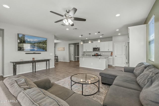 living room with recessed lighting, wood finished floors, visible vents, a ceiling fan, and baseboards