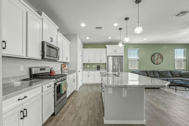 kitchen with open floor plan, appliances with stainless steel finishes, a sink, and visible vents