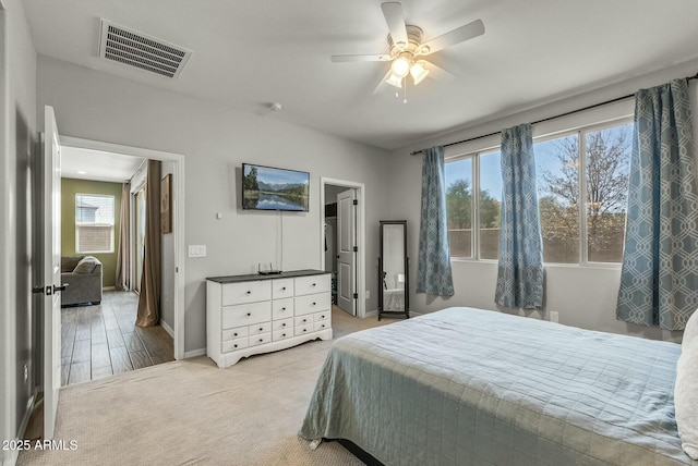 bedroom with baseboards, light carpet, visible vents, and multiple windows