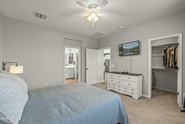 bedroom with a closet, a spacious closet, light carpet, baseboards, and visible vents