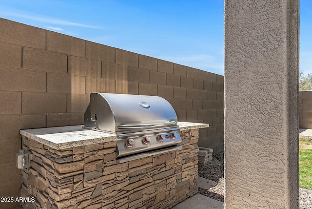 view of patio featuring a grill, fence, and exterior kitchen