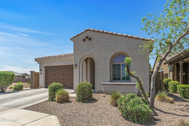 mediterranean / spanish-style home featuring concrete driveway, a tile roof, stucco siding, and a garage