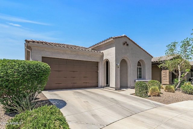 mediterranean / spanish-style home with concrete driveway, an attached garage, a tile roof, and stucco siding