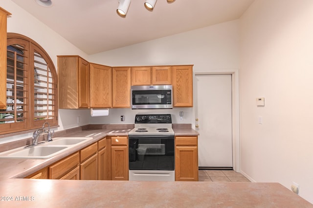 kitchen with stainless steel appliances, light tile patterned flooring, sink, and vaulted ceiling