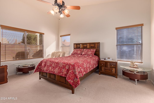 bedroom featuring light colored carpet, ceiling fan, and a high ceiling