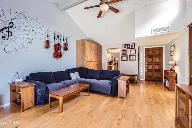 living room with visible vents, baseboards, a ceiling fan, light wood-style flooring, and beamed ceiling