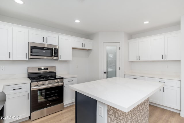 kitchen with a center island, appliances with stainless steel finishes, light hardwood / wood-style flooring, and white cabinets