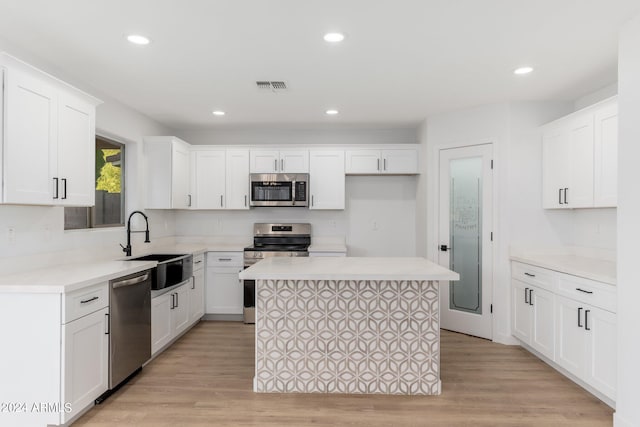 kitchen with a kitchen island, white cabinets, light hardwood / wood-style flooring, and stainless steel appliances