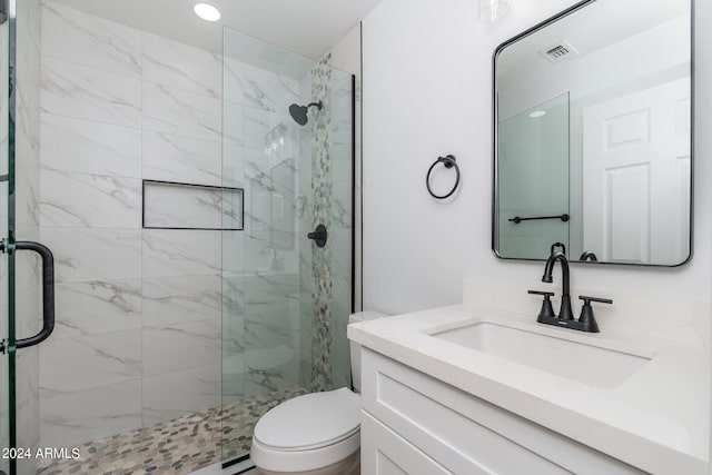 bathroom with toilet, vanity, and a shower with door