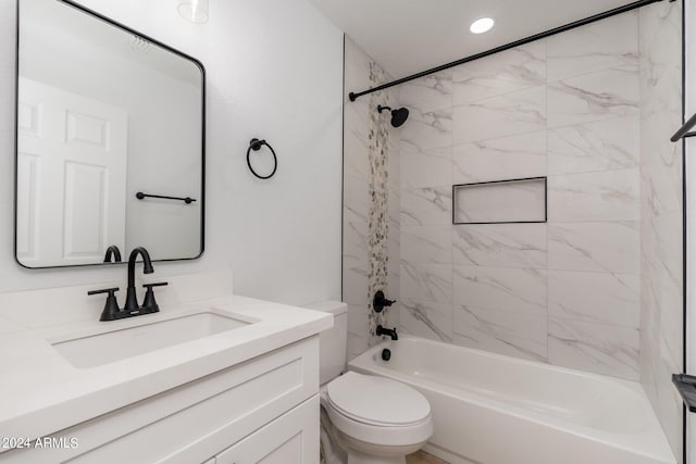 full bathroom featuring vanity, tiled shower / bath combo, and toilet