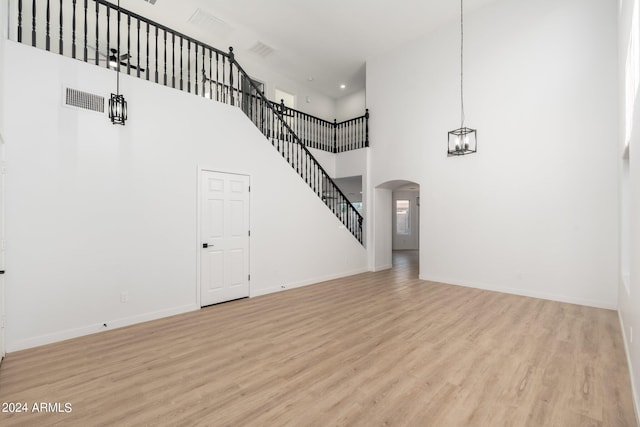 unfurnished living room featuring light hardwood / wood-style floors and a high ceiling