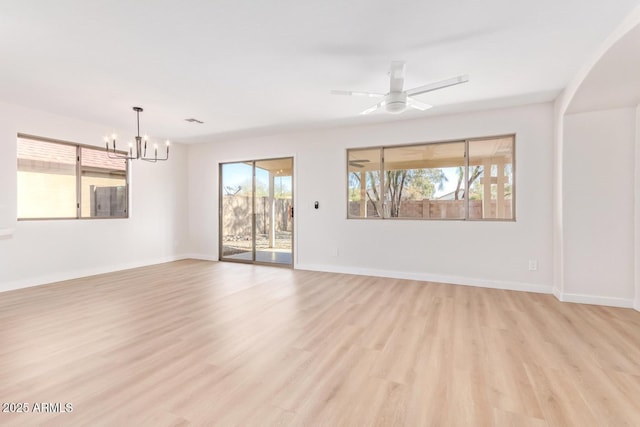 spare room featuring ceiling fan with notable chandelier and light wood-type flooring