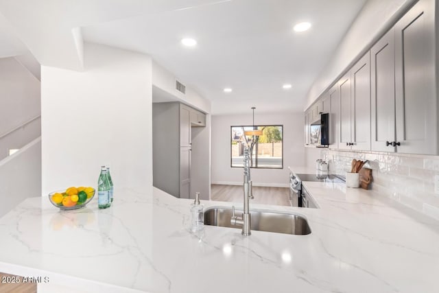 kitchen with sink, stainless steel electric range, gray cabinetry, backsplash, and light stone counters