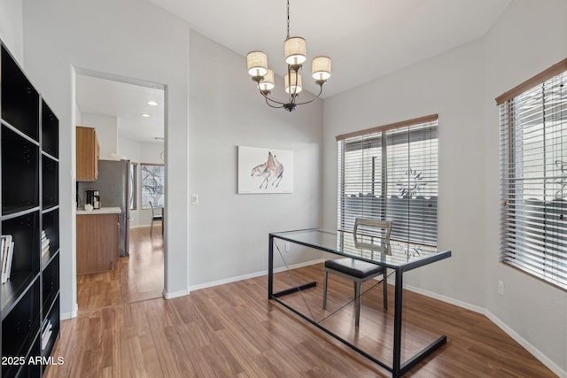 dining space with baseboards, a notable chandelier, and light wood-style floors