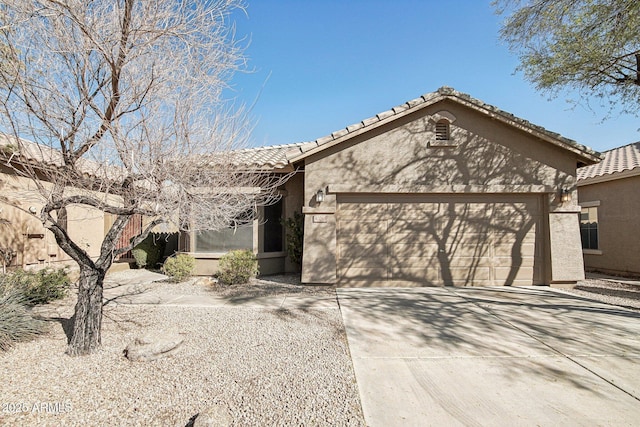 view of front facade featuring a garage, driveway, a tiled roof, and stucco siding