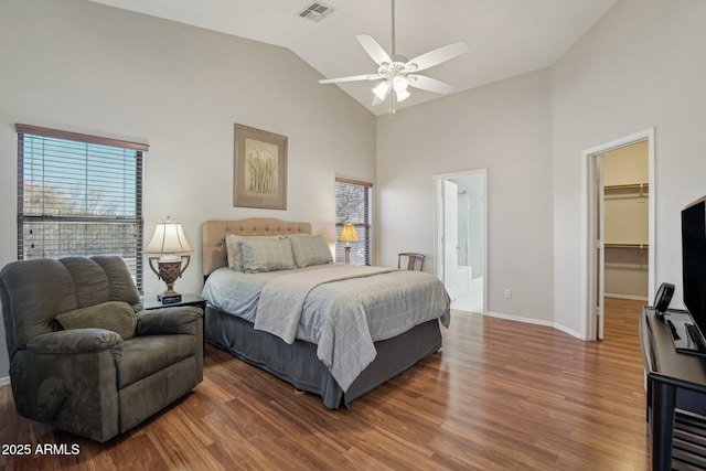 bedroom with a spacious closet, multiple windows, visible vents, and wood finished floors