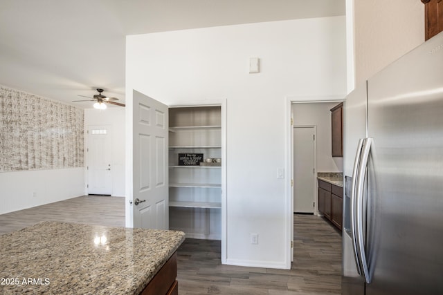 kitchen with light stone counters, stainless steel fridge with ice dispenser, dark hardwood / wood-style floors, and ceiling fan