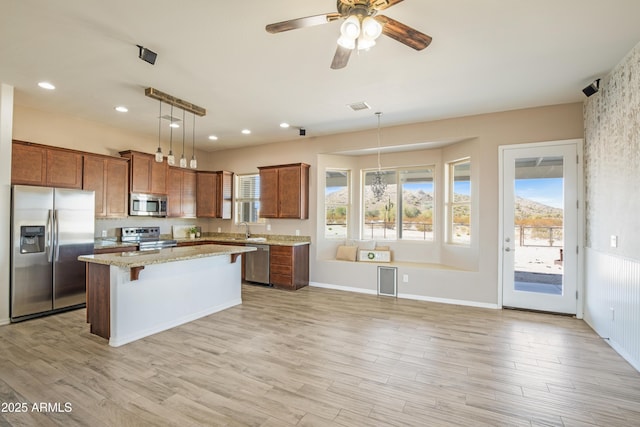 kitchen with sink, appliances with stainless steel finishes, a center island, a kitchen bar, and decorative light fixtures