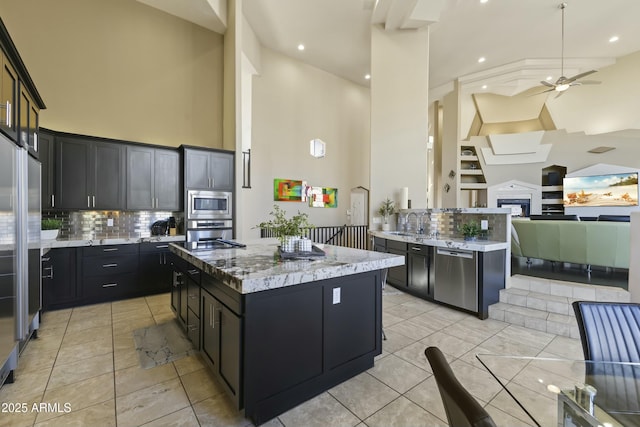 kitchen with backsplash, a center island, a high ceiling, and appliances with stainless steel finishes