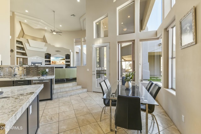 kitchen with dishwasher, backsplash, sink, ceiling fan, and light stone countertops