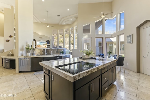 kitchen with ceiling fan, a center island, a high ceiling, backsplash, and black electric cooktop