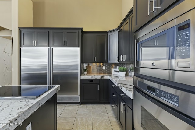 kitchen with light stone countertops, black electric stovetop, tasteful backsplash, double wall oven, and built in refrigerator