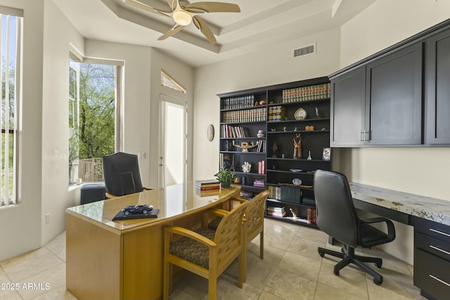 office with light tile patterned floors, built in desk, a tray ceiling, and ceiling fan