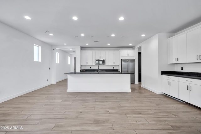 kitchen with sink, white cabinetry, stainless steel appliances, and an island with sink