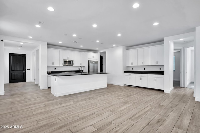 kitchen featuring sink, white cabinets, a center island with sink, and stainless steel appliances