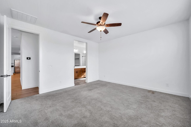 unfurnished bedroom featuring light carpet, ceiling fan, and ensuite bathroom