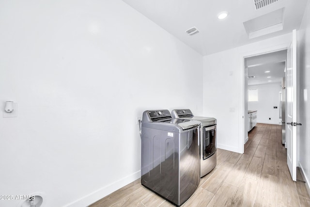 laundry area featuring light wood-type flooring and washing machine and dryer