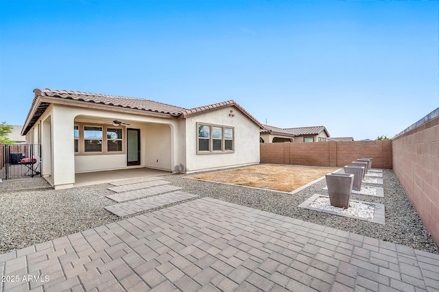 rear view of property featuring ceiling fan and a patio area