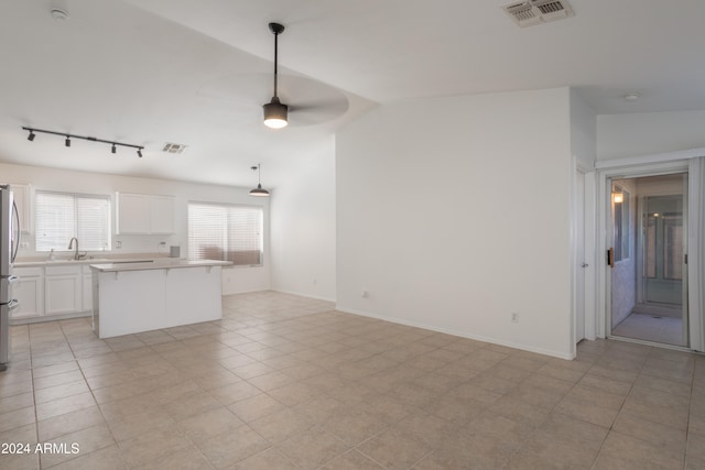 unfurnished living room with ceiling fan, light tile patterned floors, sink, and vaulted ceiling