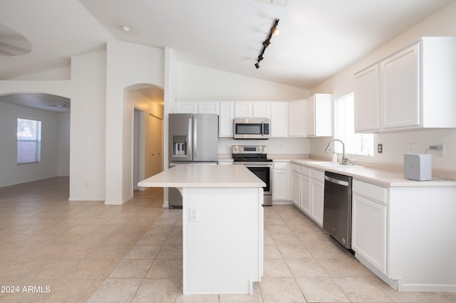 kitchen with a center island, white cabinets, sink, vaulted ceiling, and appliances with stainless steel finishes