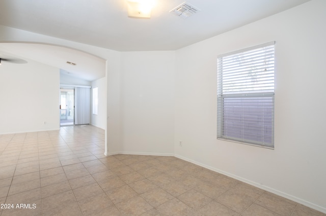 empty room with light tile patterned floors, lofted ceiling, and a healthy amount of sunlight