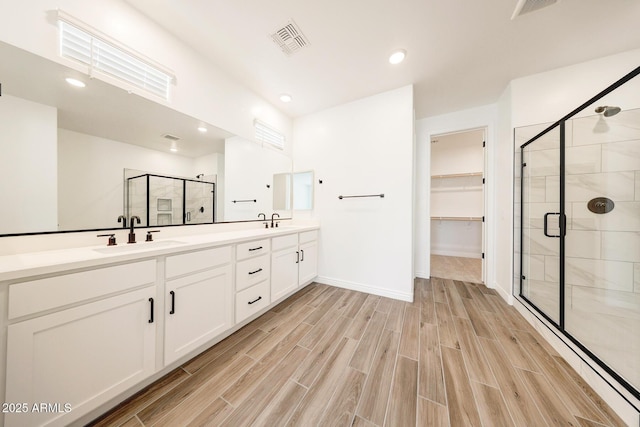 14742 W Lariat Trl, Surprise, AZ 85387 - bathroom with a stall shower, double vanity, wood finished floors, a walk in closet, and recessed lighting