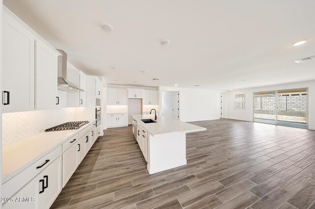 14742 W Lariat Trl, Surprise, AZ 85387 - kitchen featuring wall chimney exhaust hood, open floor plan, stovetop, wood finished floors, and recessed lighting