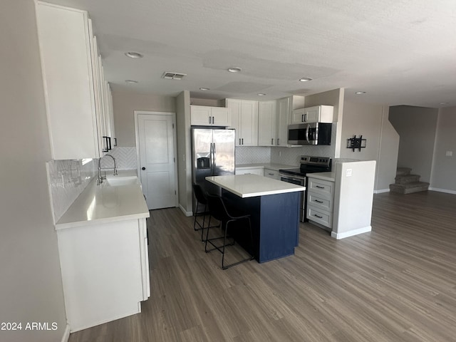 kitchen featuring a breakfast bar area, stainless steel appliances, a center island, sink, and white cabinetry