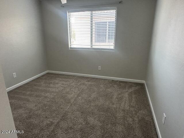 spare room featuring dark colored carpet