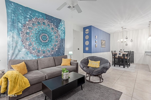 living room with light tile patterned flooring and ceiling fan with notable chandelier