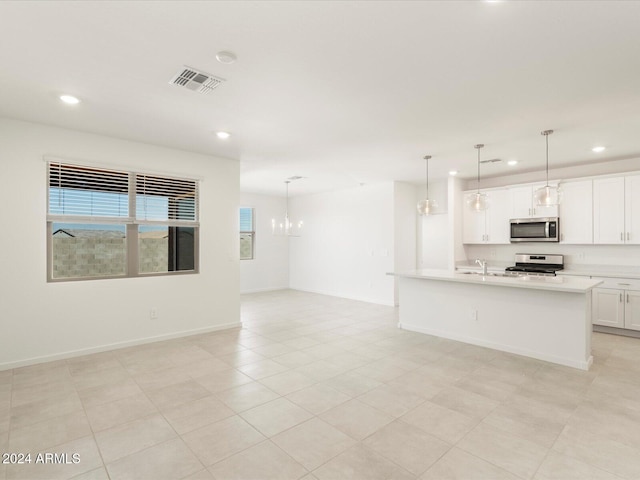 kitchen with white cabinets, a center island with sink, a chandelier, pendant lighting, and stainless steel appliances