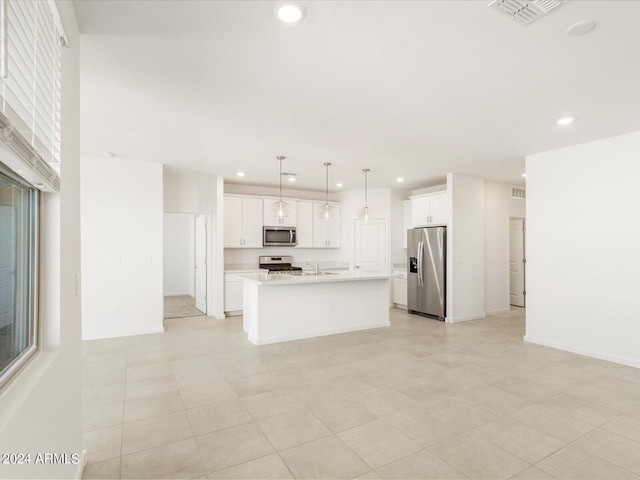 kitchen with a center island with sink, sink, pendant lighting, white cabinetry, and appliances with stainless steel finishes